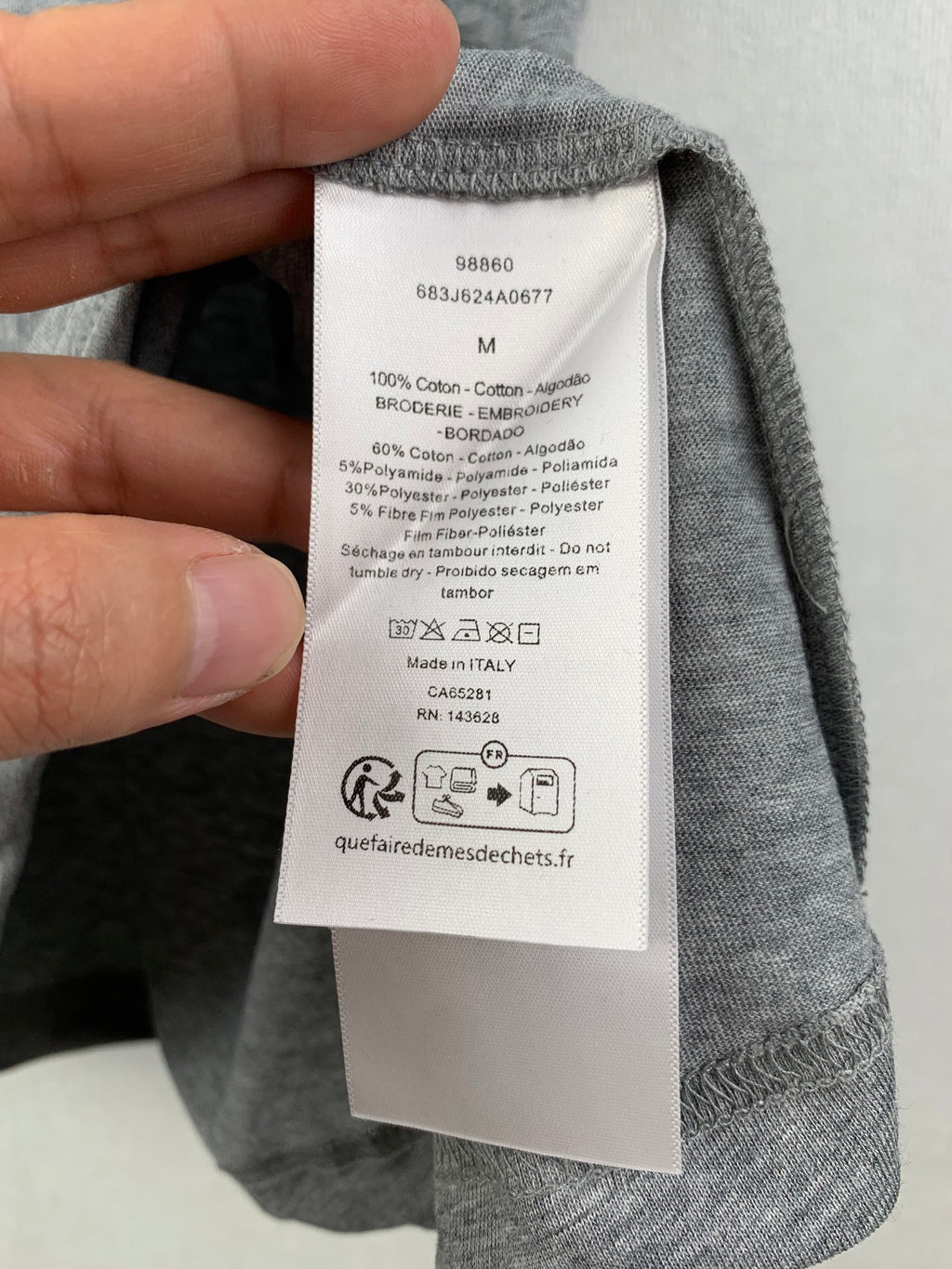 Gray T-shirt care label showing size M and material composition.