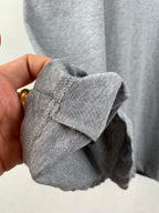 Gray T-shirt cuff and stitched hem detail, close-up held by hand.