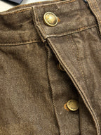 Brown denim jeans close-up, gold button detail and visible stitching