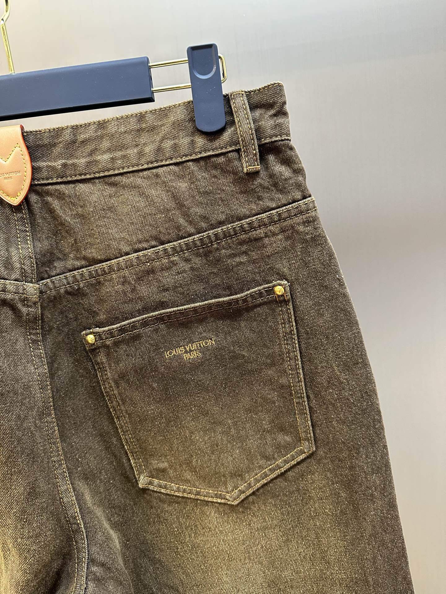 Brown denim jeans close-up, front pocket with Louis Vuitton label
