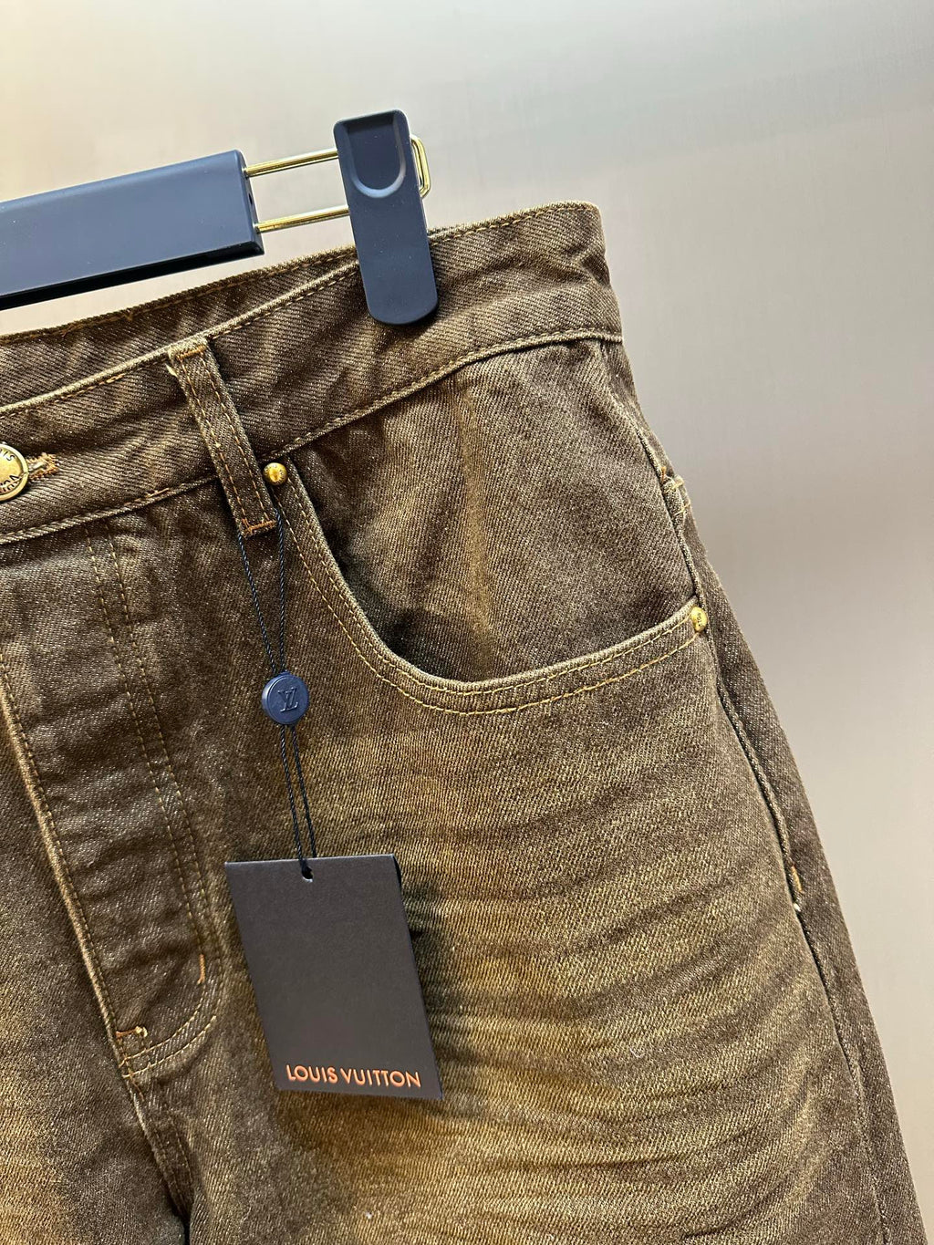 Brown denim jeans close-up, curved front pocket and waistband tag