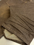 Brown denim jeans close-up, pleated fabric and stitched hem