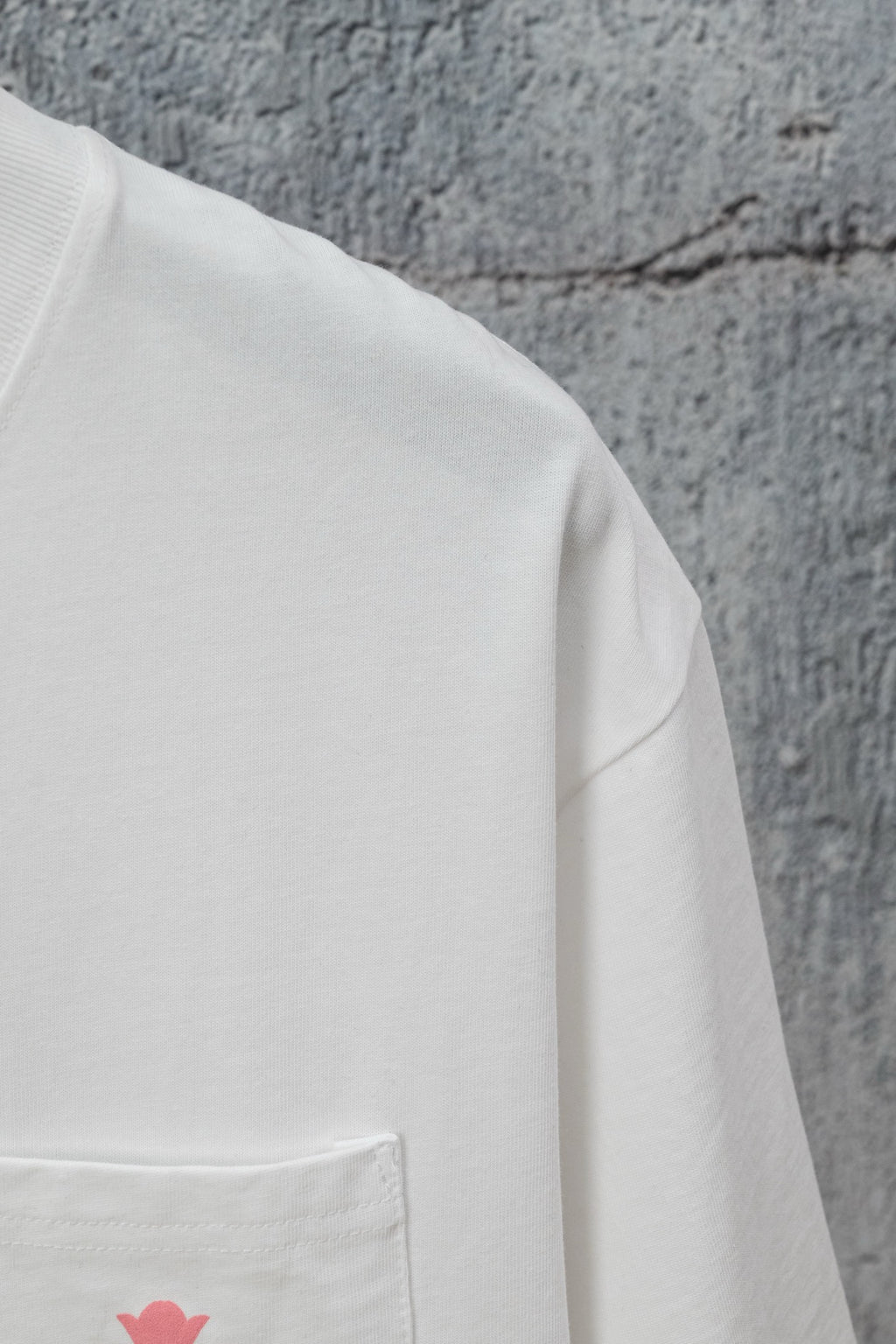 White short-sleeve T-shirt with side pocket seam and small pink logo mark