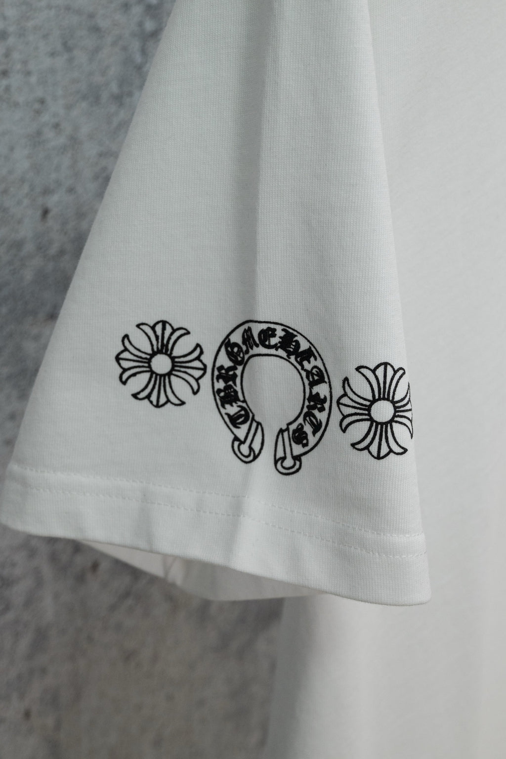 White T-shirt hem with small flower and horseshoe graphic print