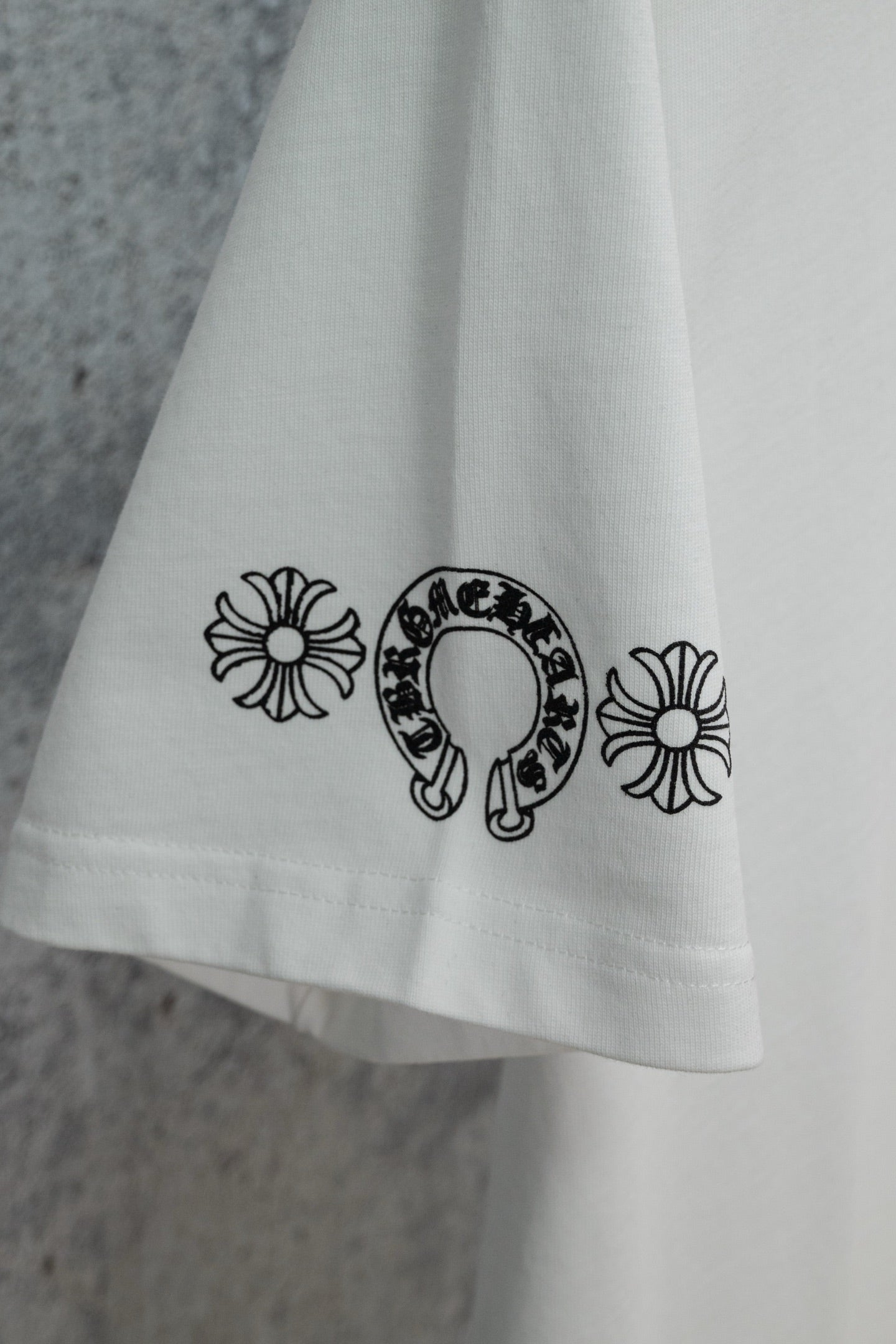 White T-shirt hem with small flower and horseshoe graphic print