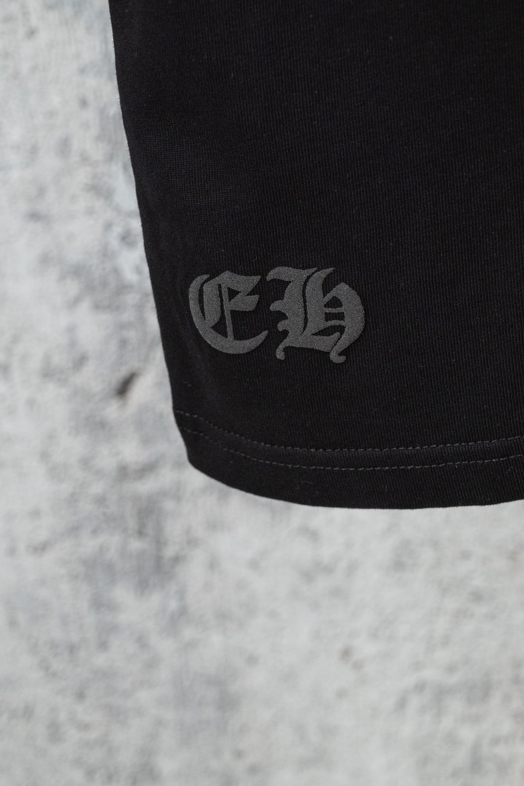 Black short-sleeve T-shirt close-up of small embroidered emblem on sleeve hem
