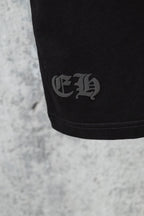 Black short-sleeve T-shirt close-up of small embroidered emblem on sleeve hem