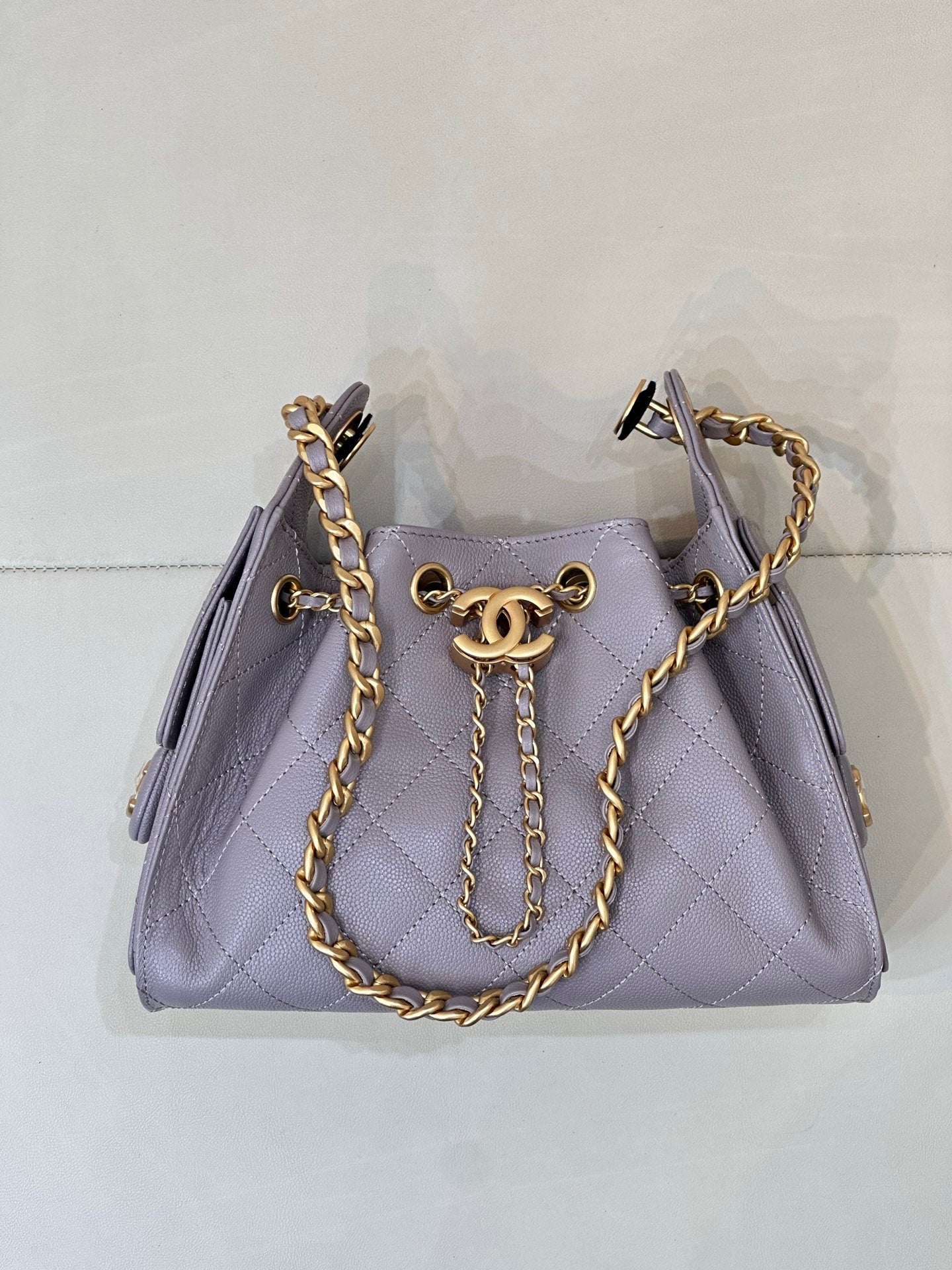 Lavender quilted top-handle bag with gold chain handles and front CC charm