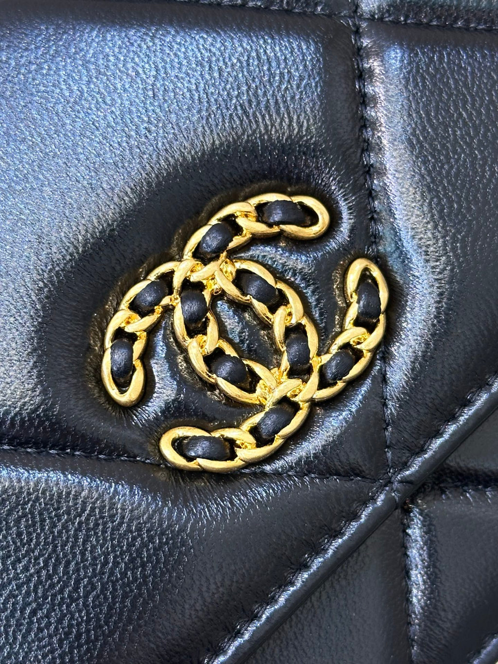 Chanel quilted flap detail with gold CC emblem on dark blue leather bag