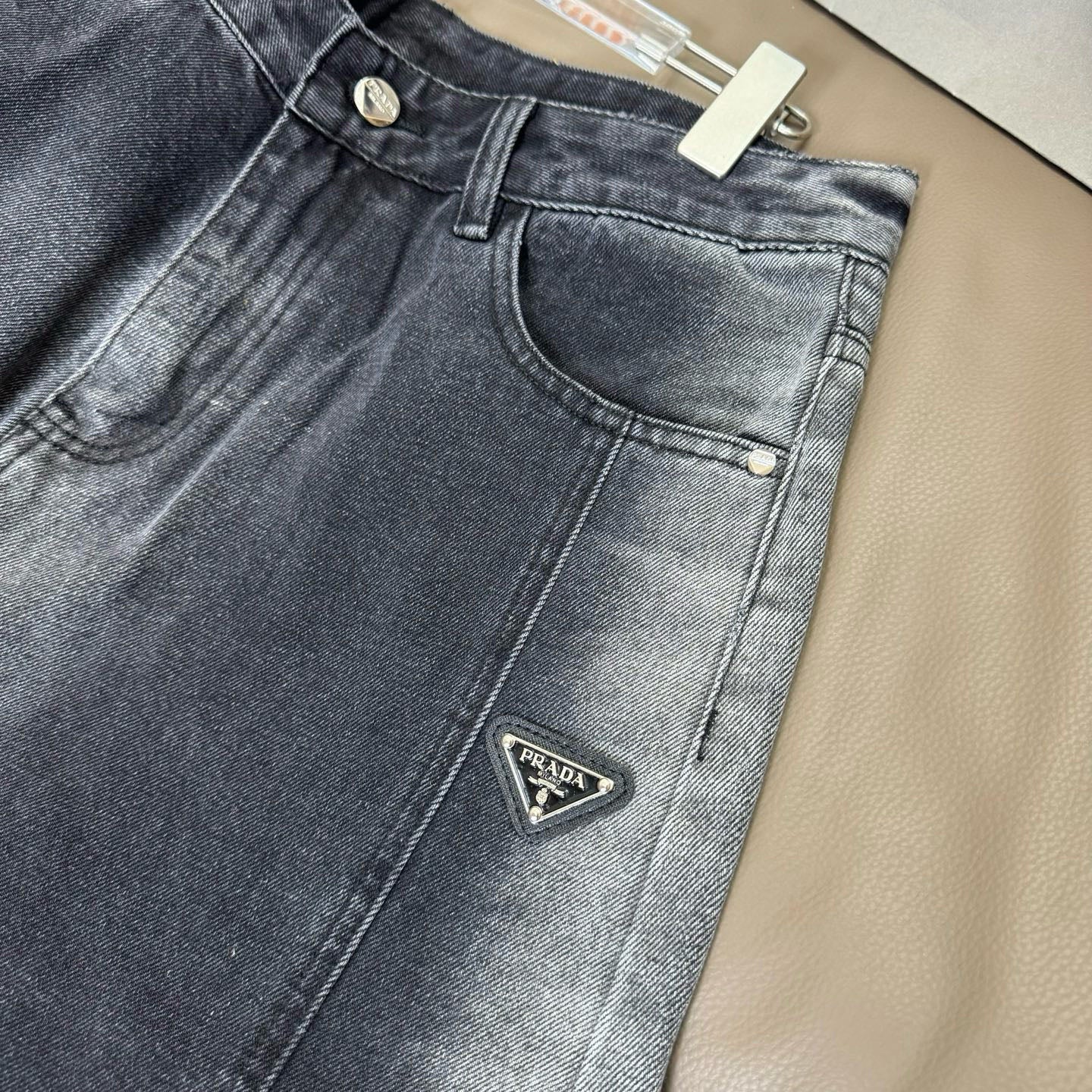 Dark blue denim pants with button fly, front pockets, and Prada logo patch