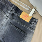 Dark blue denim waistband close-up with Prada orange tag and belt loops
