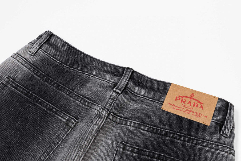 Dark gray denim pants with PRADA leather logo patch at waistband
