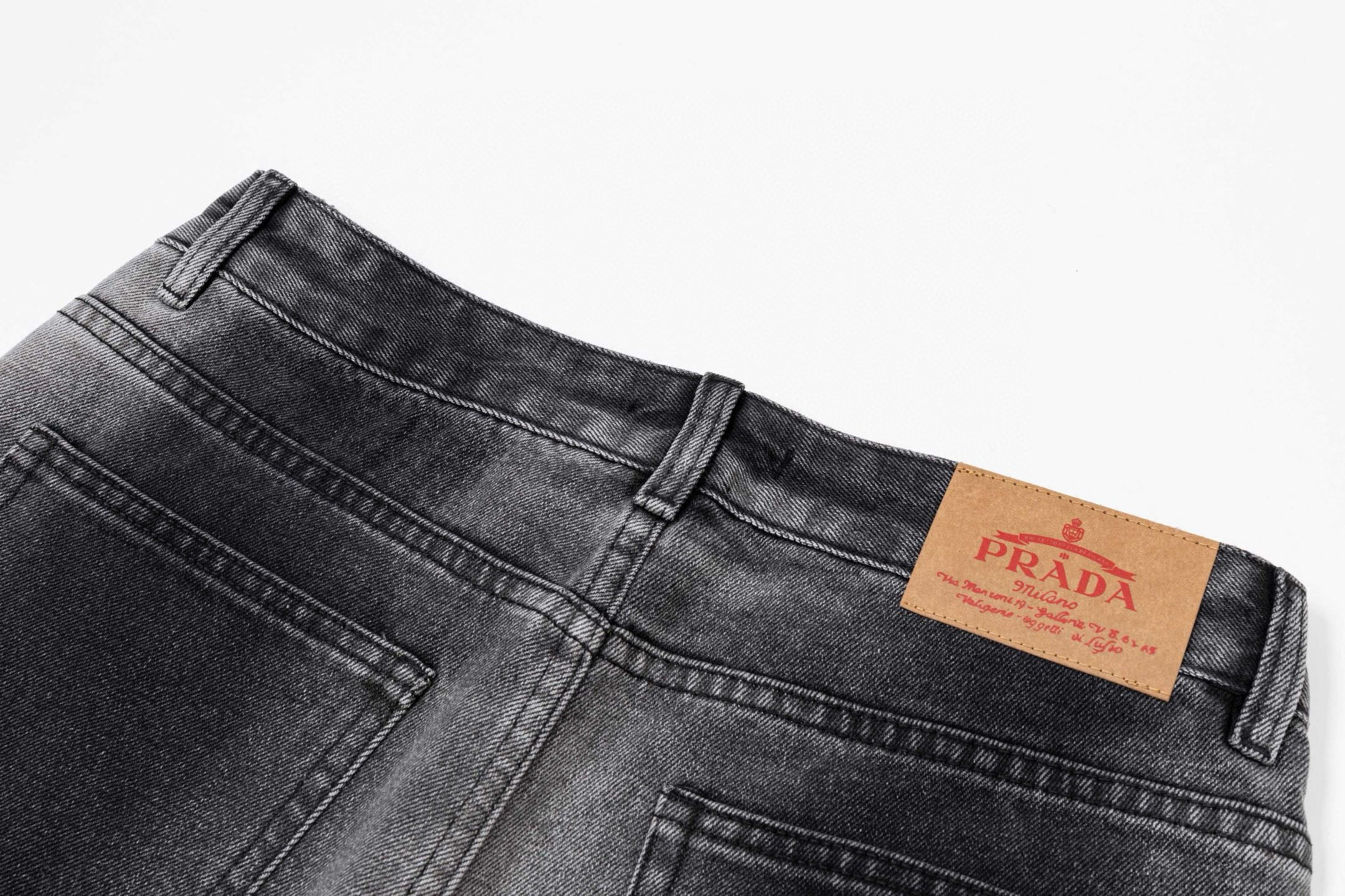 Dark gray denim pants with PRADA leather logo patch at waistband