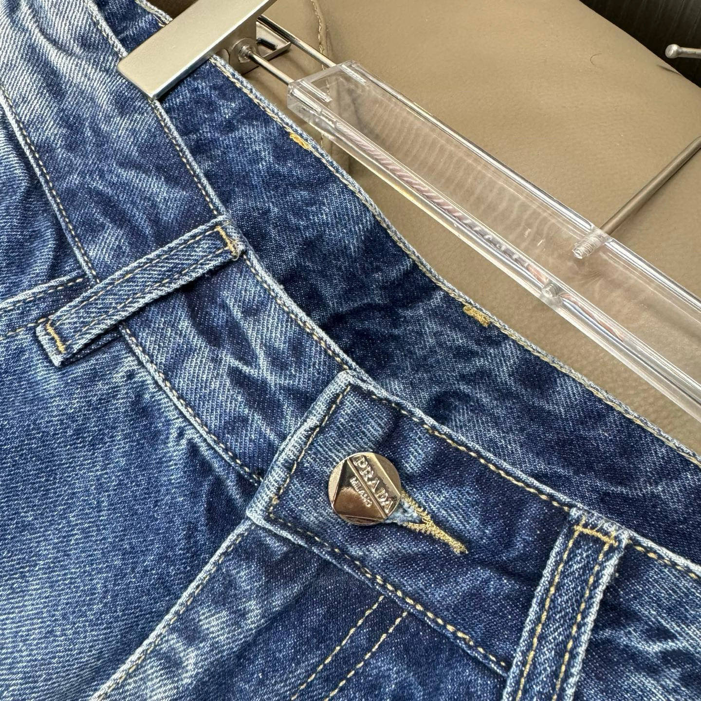 Light blue denim pants close-up of belt loops, button, and stitched seams