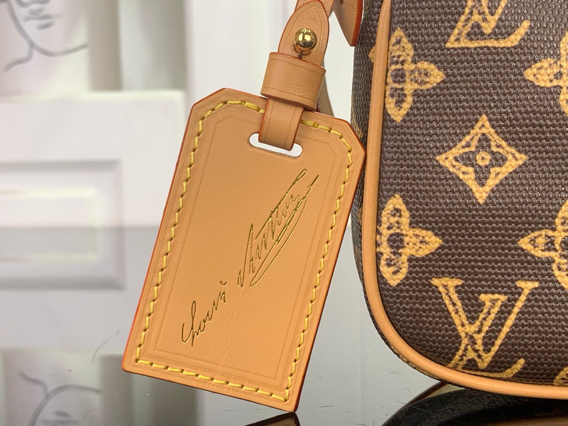 Louis Vuitton monogram bag with tan leather luggage tag and gold loop hardware