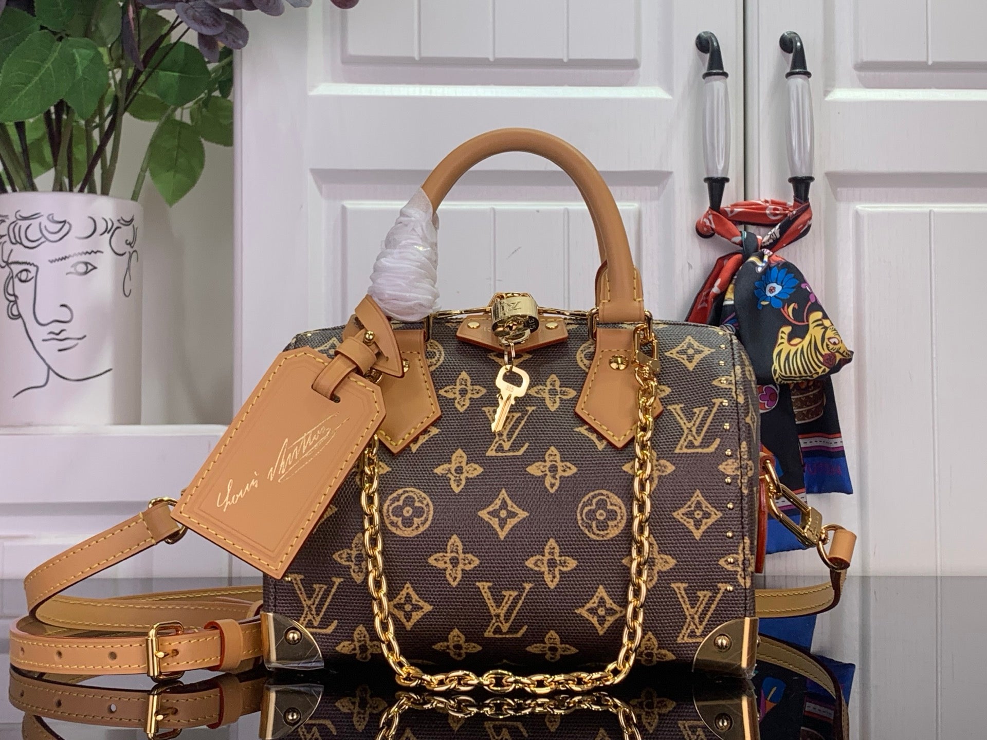 Louis Vuitton monogram handbag with tan strap and gold hardware, front view