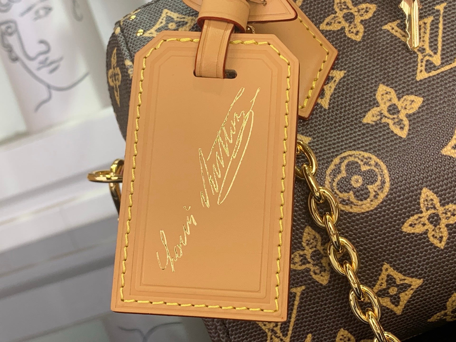 Louis Vuitton monogram handbag leather charm, tan patch with stamped script, close-up