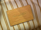 Louis Vuitton logo patch on striped canvas pouch with tan leather trim, close-up