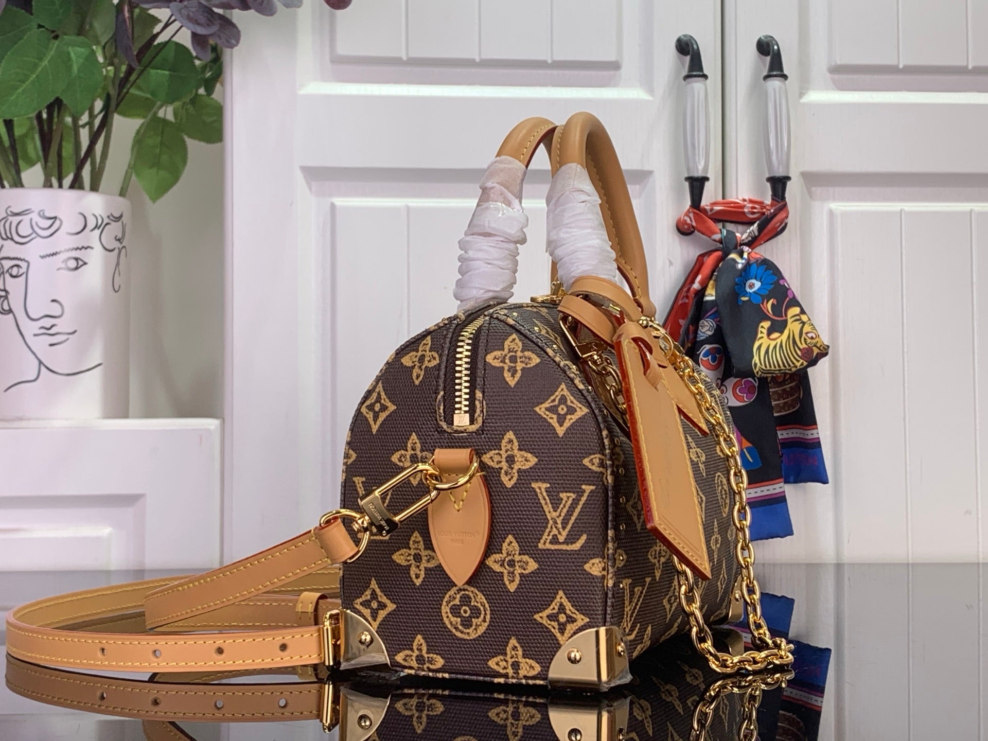 Louis Vuitton monogram mini handbag with tan shoulder strap and gold chain, side view