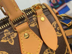 Tan leather strap and corner hardware on brown monogram bag, with gold-tone fittings.