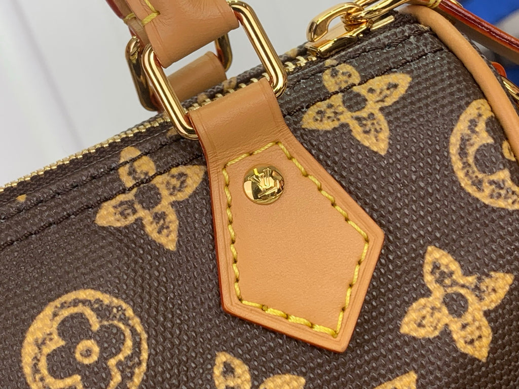 Tan leather patch with gold logo rivet on brown monogram bag, stitched border.