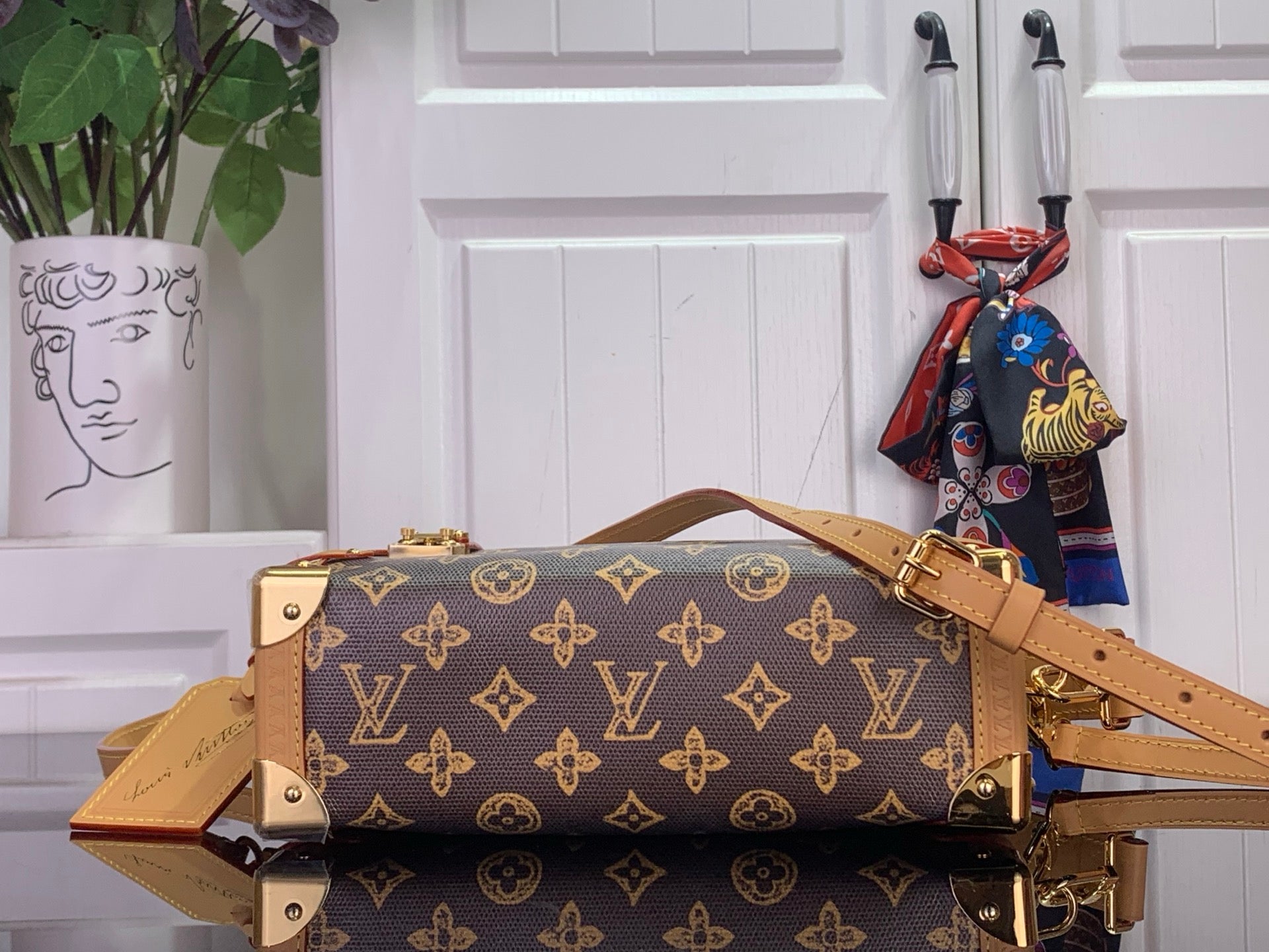 Louis Vuitton monogram handbag with tan straps and gold-tone hardware, side view