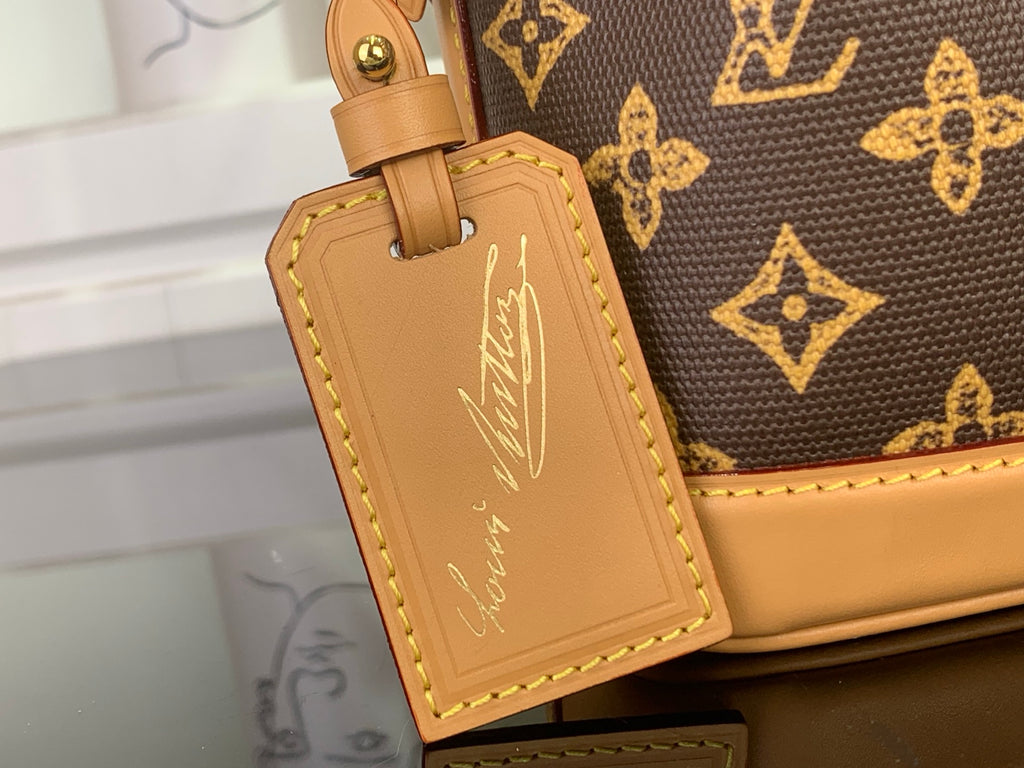 Tan leather luggage tag charm attached to monogram mini bag