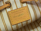 White monogram bag fabric tag with gold text celebrating 130 years