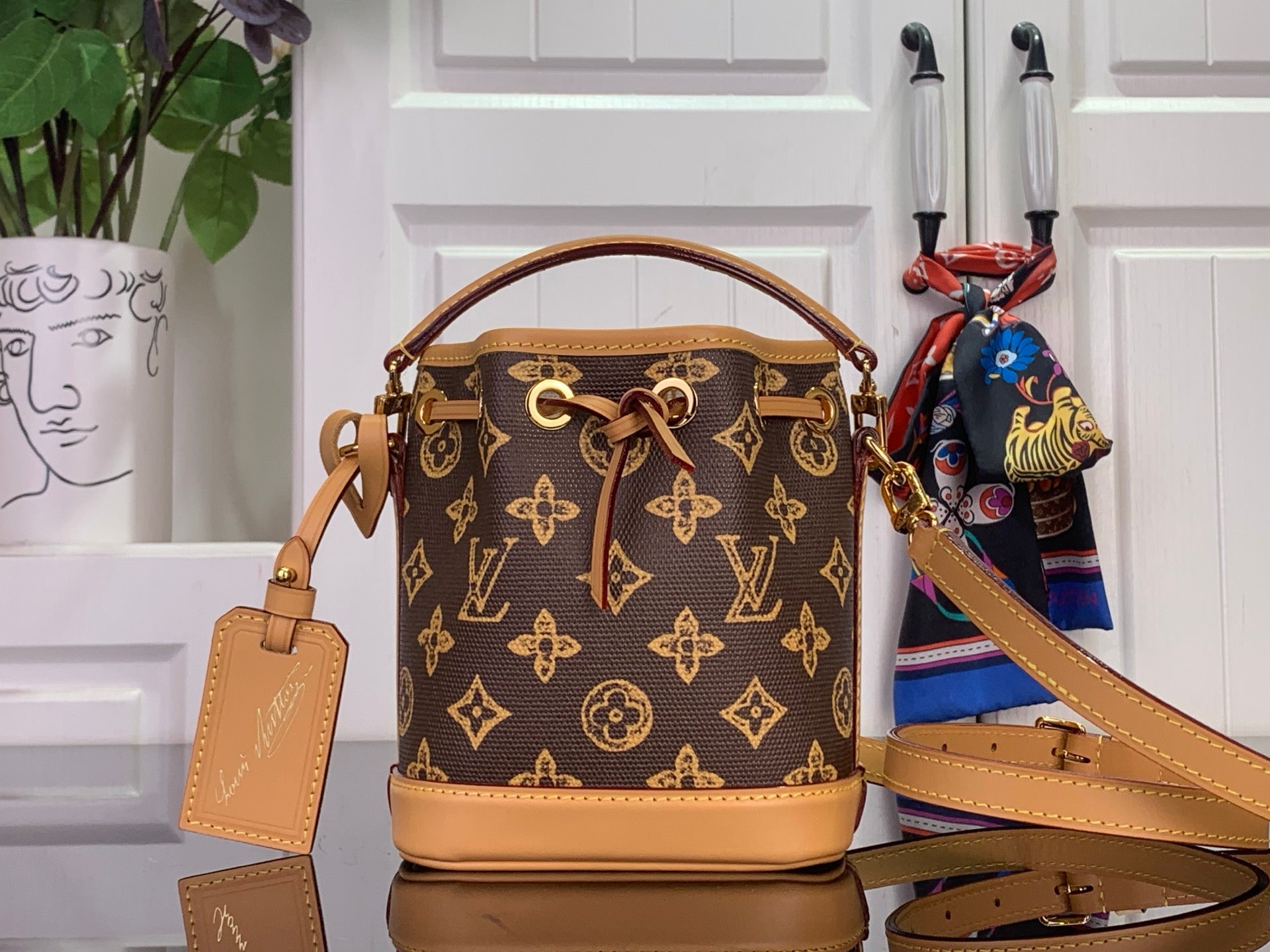 Monogram mini bucket bag with tan leather handles and crossbody strap