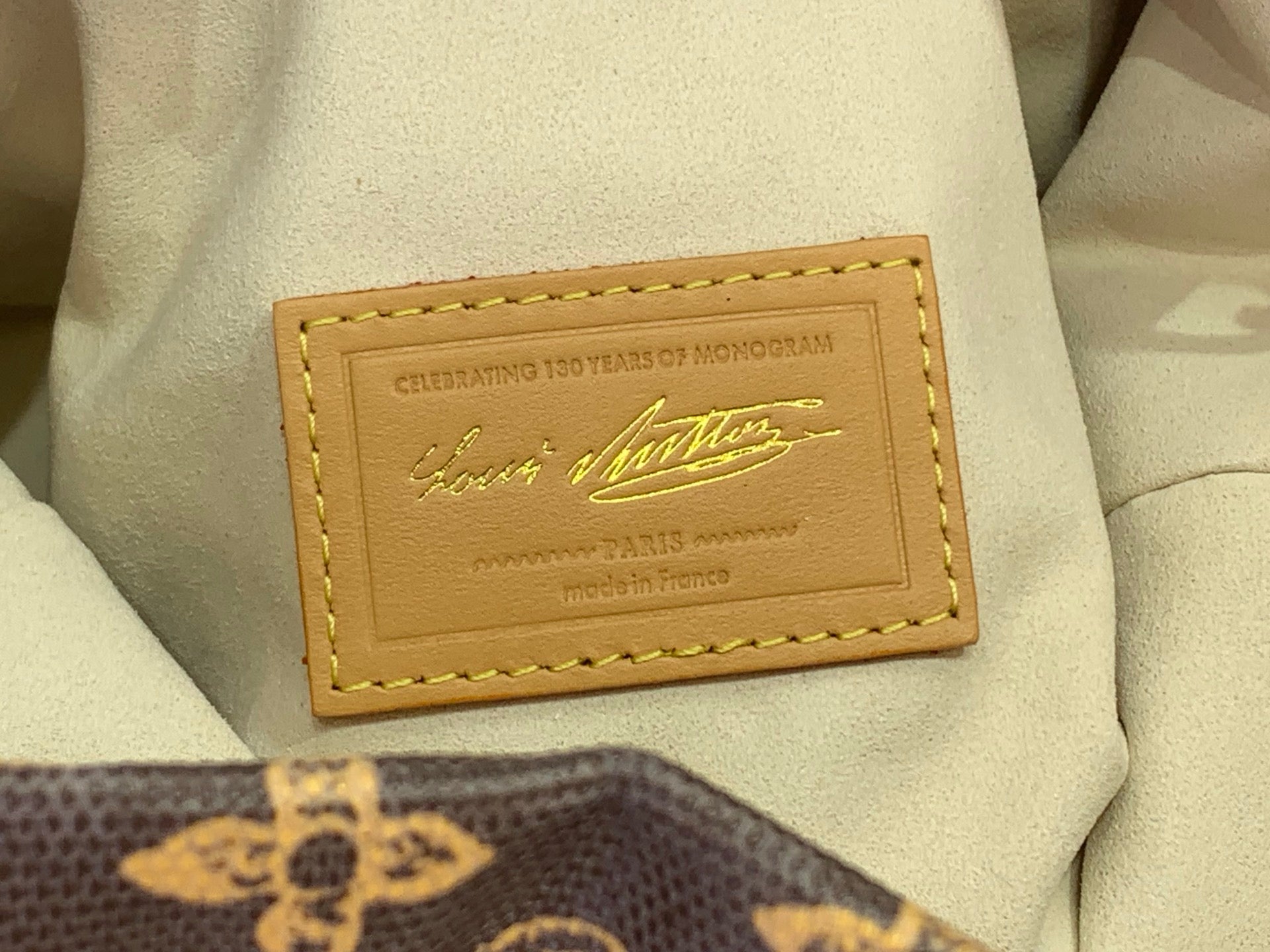 Cream interior label pocket with gold printed branding and stitched leather border