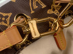 Gold-tone clasp and chain link hardware with tan leather strap on monogram canvas