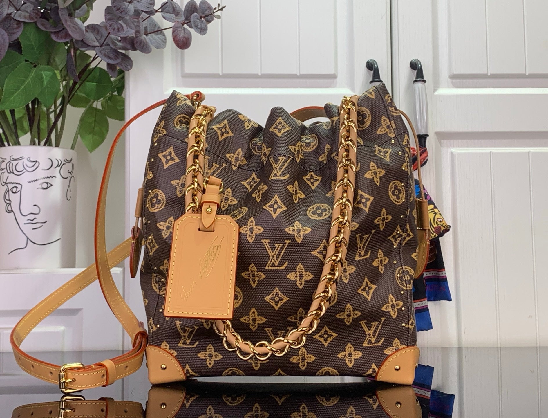 Louis Vuitton monogram canvas bucket bag with tan leather trim and gold chain strap