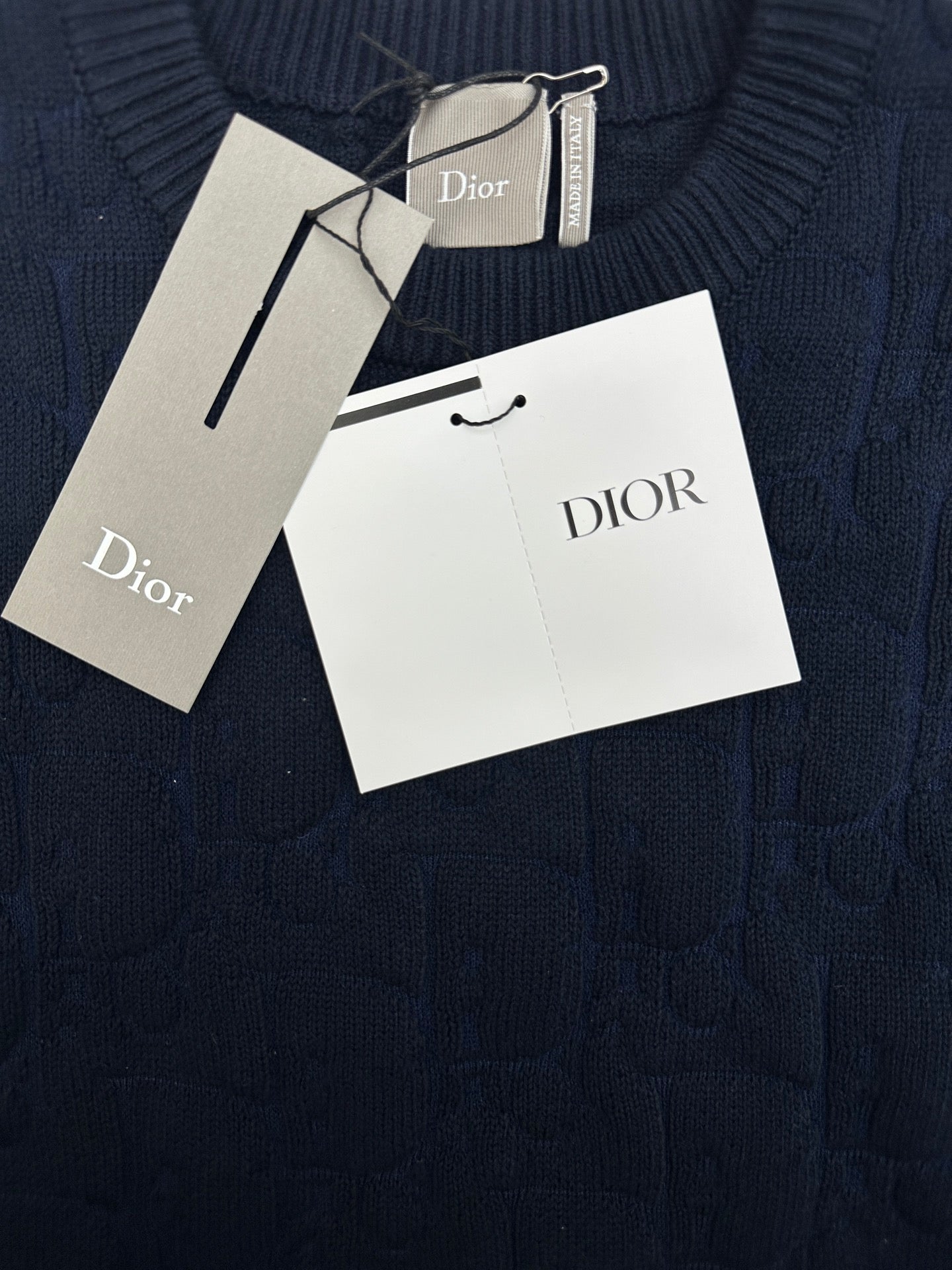 Navy knit sweater fabric close-up with Dior hang tag and size tag