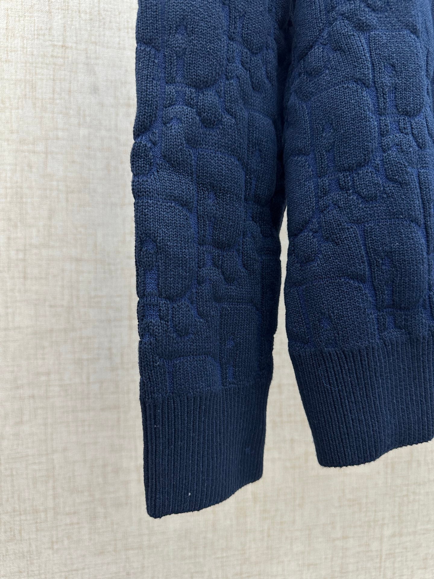 Navy knit sweater sleeves and hem, close-up view