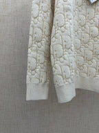 Cream knit sweater showing hem and ribbed cuffs, allover logo pattern