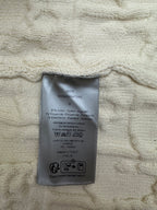 Cream sweater with attached care label inside the collar