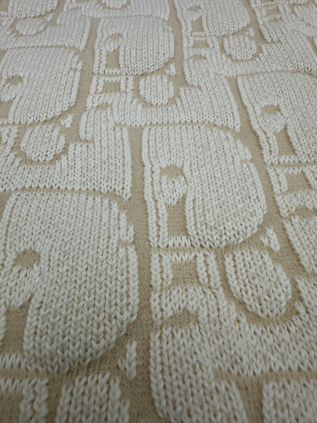 Cream knit fabric with allover geometric logo pattern texture
