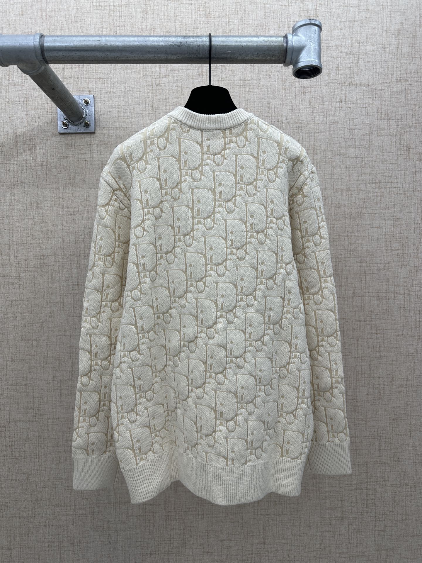 Cream knit sweater back view with allover logo pattern, ribbed crew neck and hem