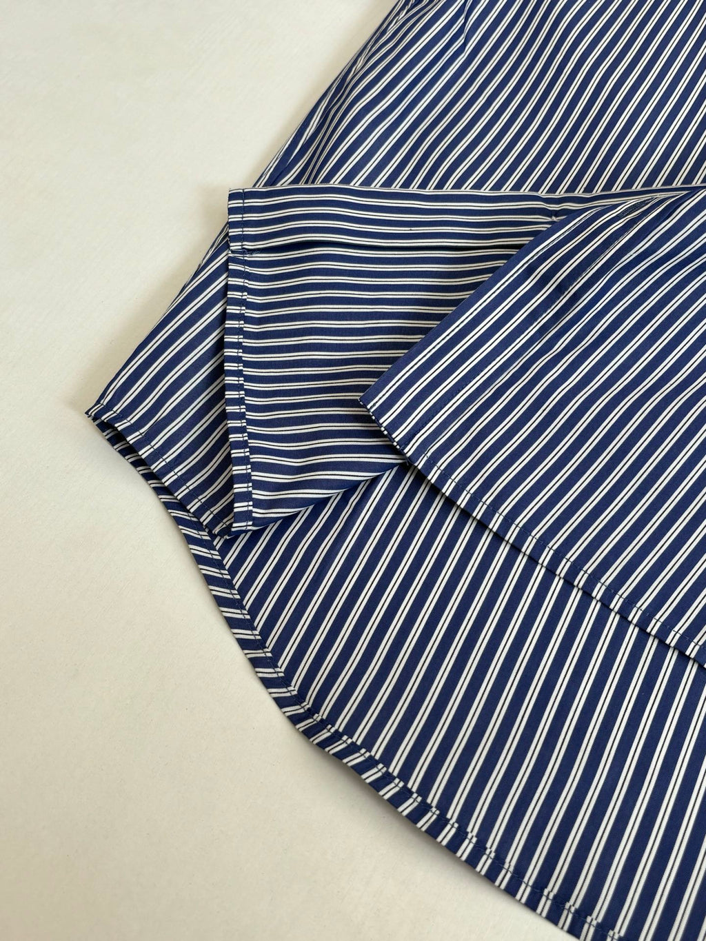 Striped button-up shirt, blue and white vertical stripes, folded with collar and sleeves
