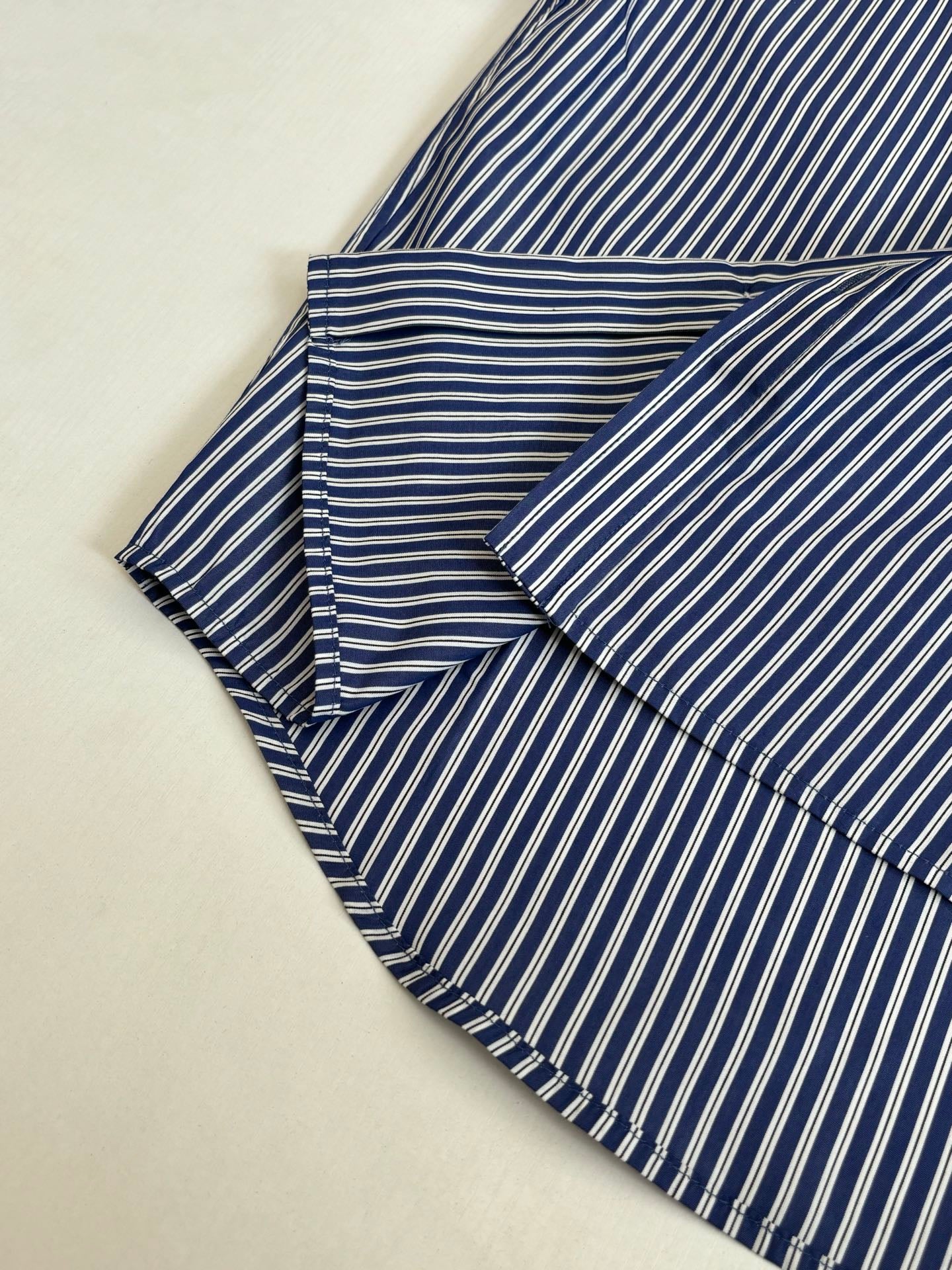Striped button-up shirt, blue and white vertical stripes, folded with collar and sleeves