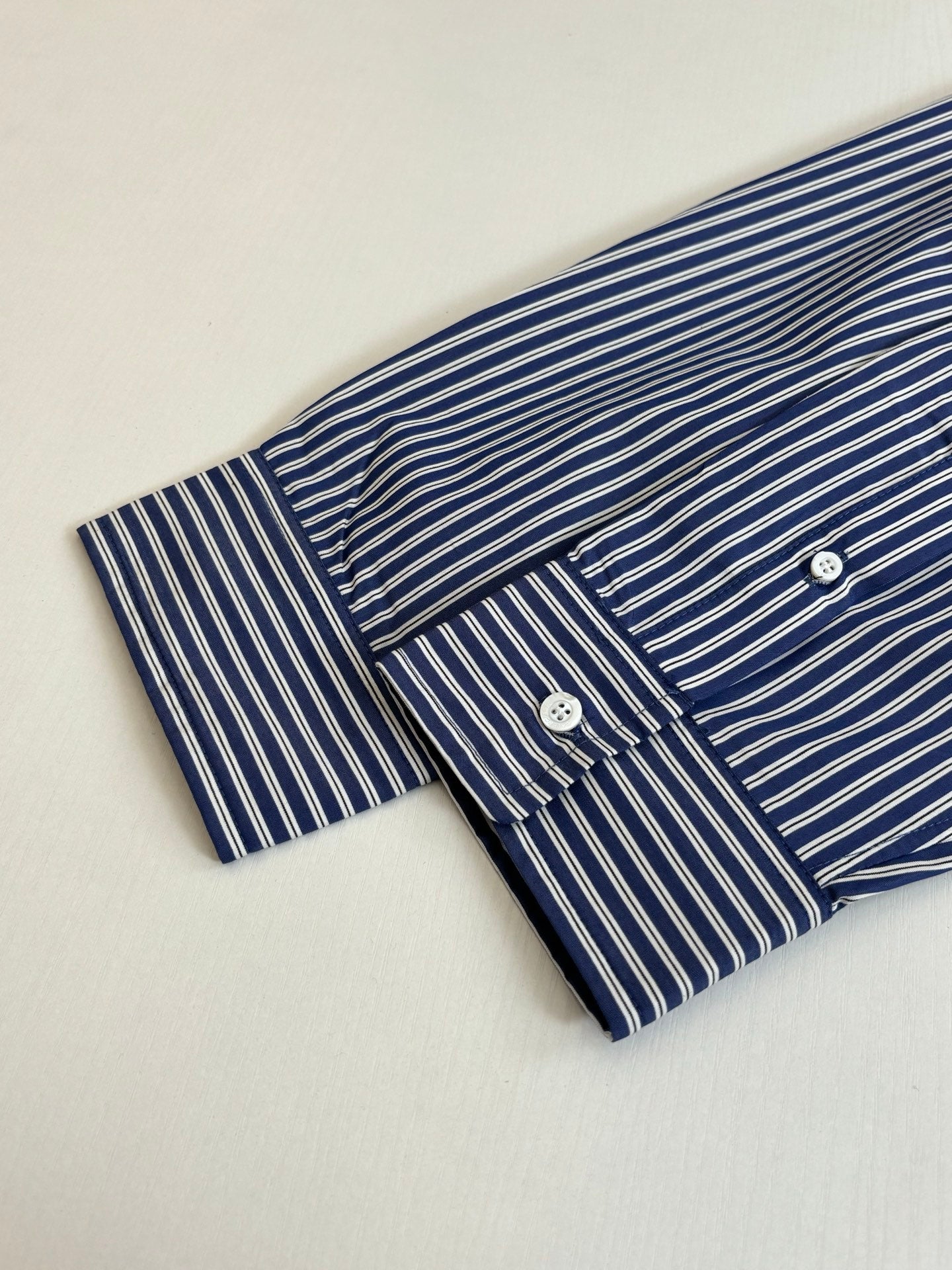 Striped button-up shirt sleeve and chest placket, blue and white vertical stripes