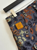 Louis Vuitton patterned shorts fabric close-up, tan patch logo on camo print