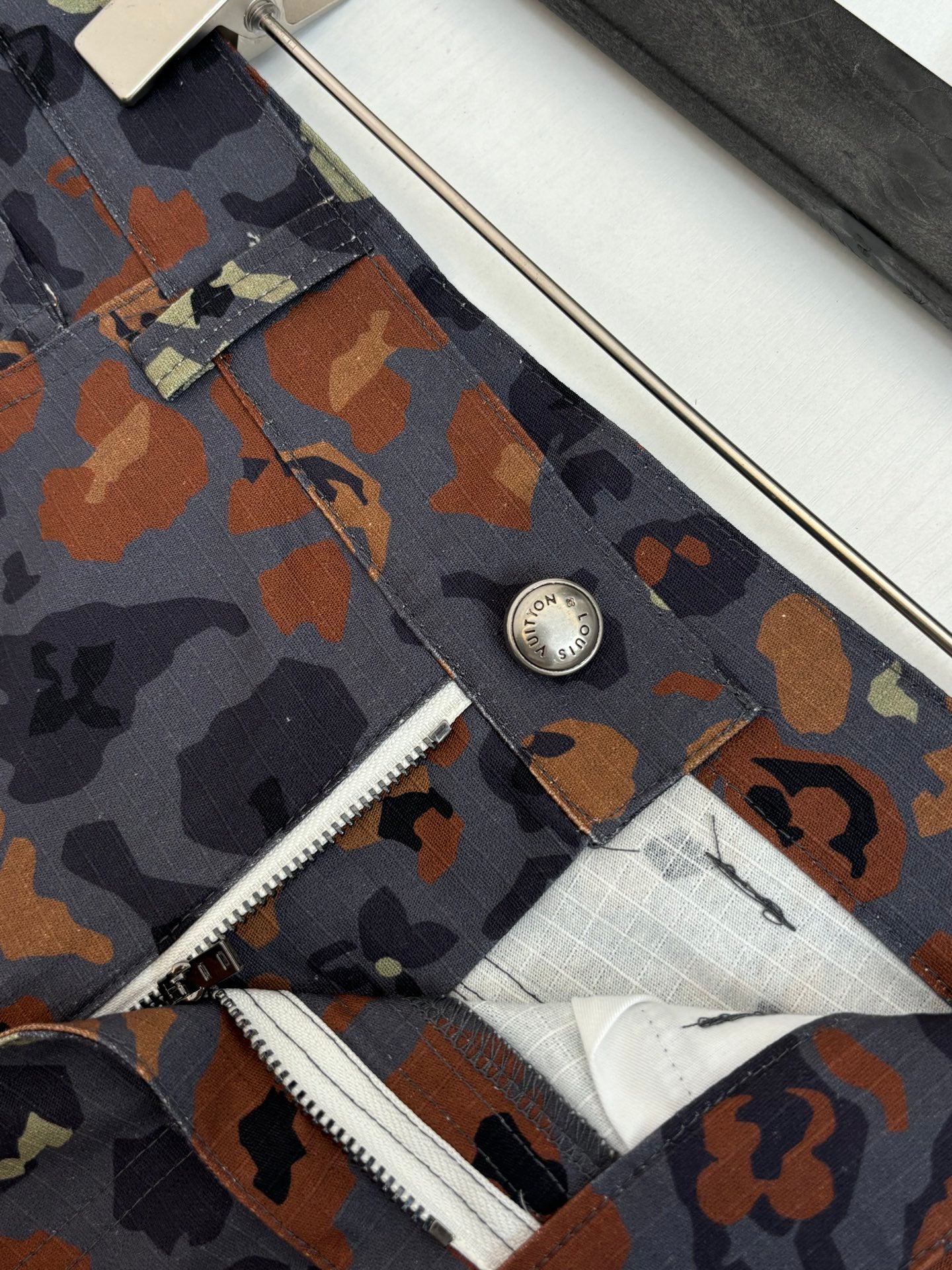 Louis Vuitton patterned shorts close-up, metal button and zipper fly seam