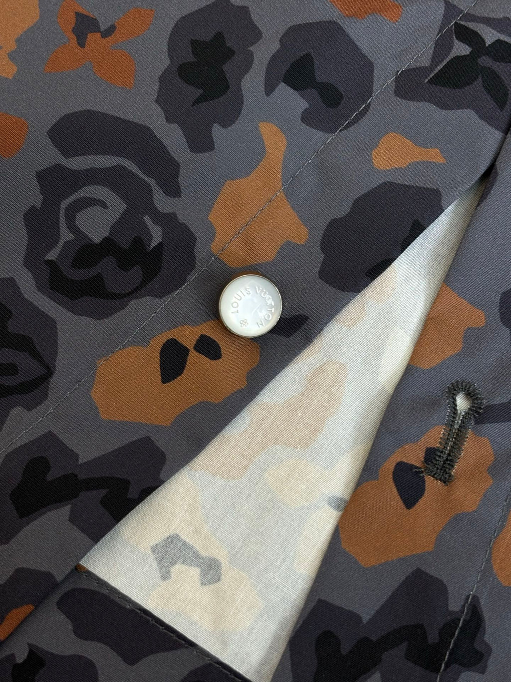 Multicolor camo shirt close-up with white button and light-beige trim at cuff