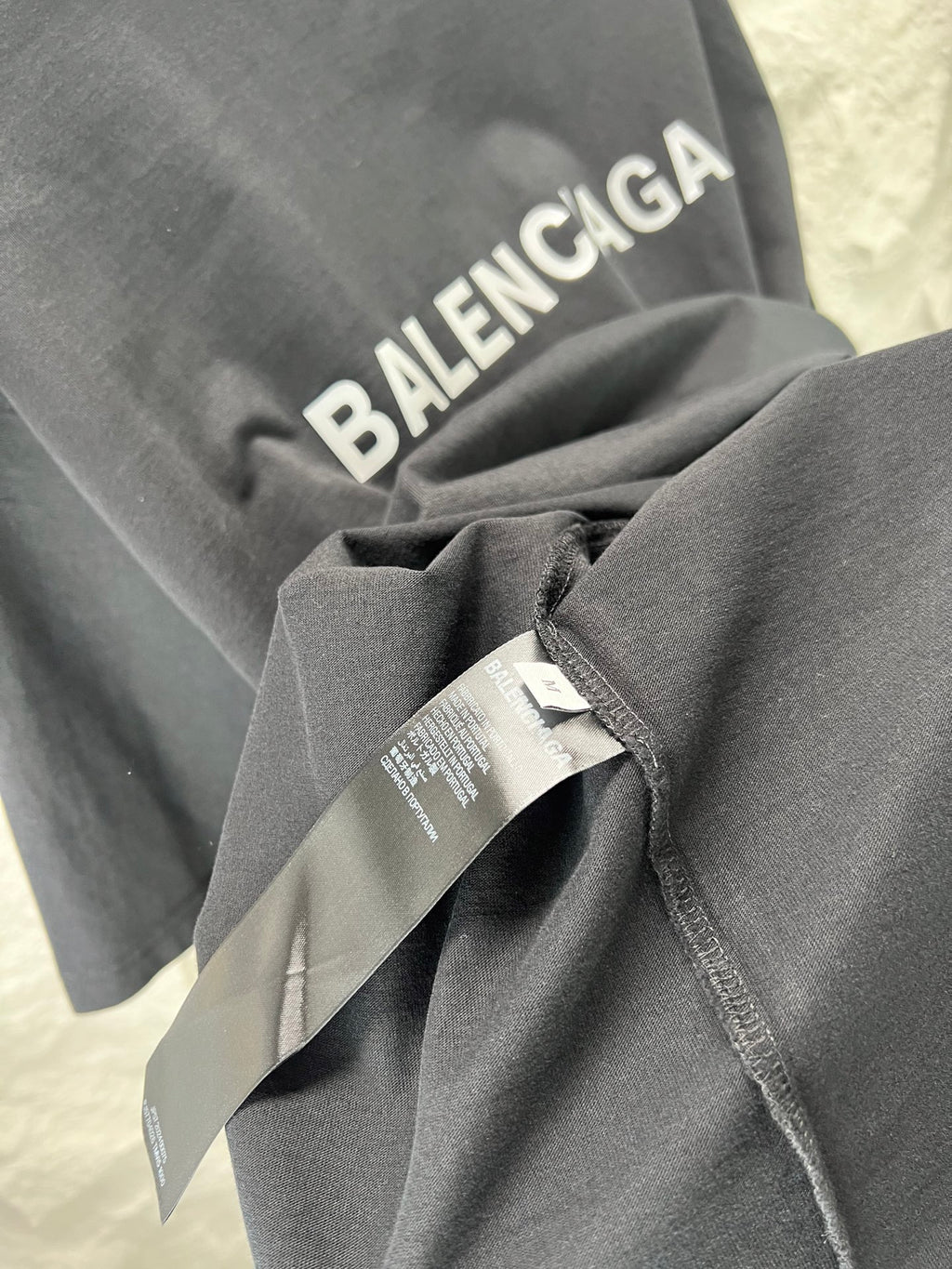 Balenciaga heather gray T-shirt sleeve with attached tag and folded fabric
