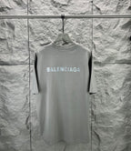Light gray crewneck T-shirt with large BALENCIAGA logo on front, on hanger