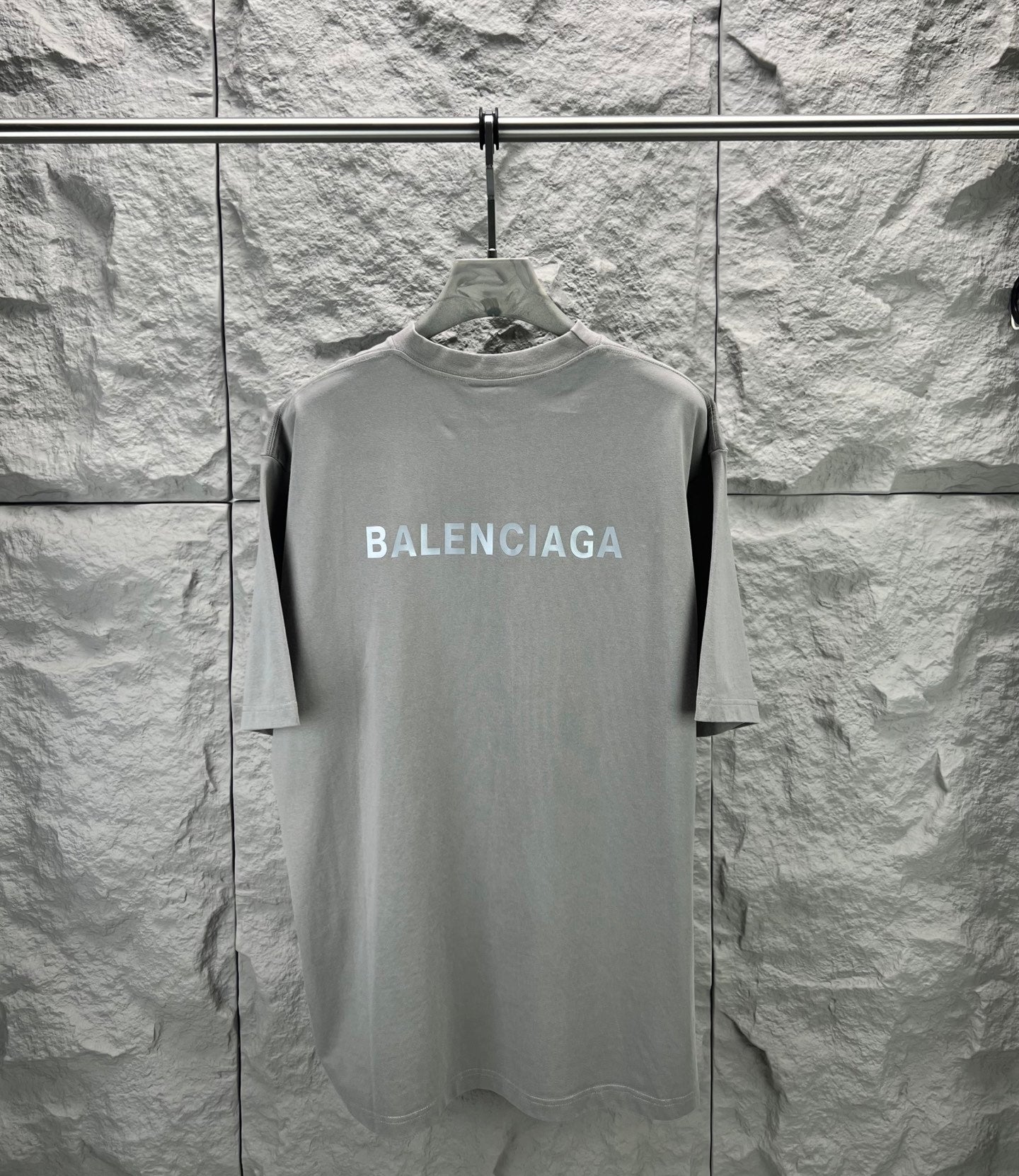 Light gray crewneck T-shirt with large BALENCIAGA logo on front, on hanger