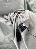 Folded light gray crewneck T-shirt with BALENCIAGA tag and fabric drape