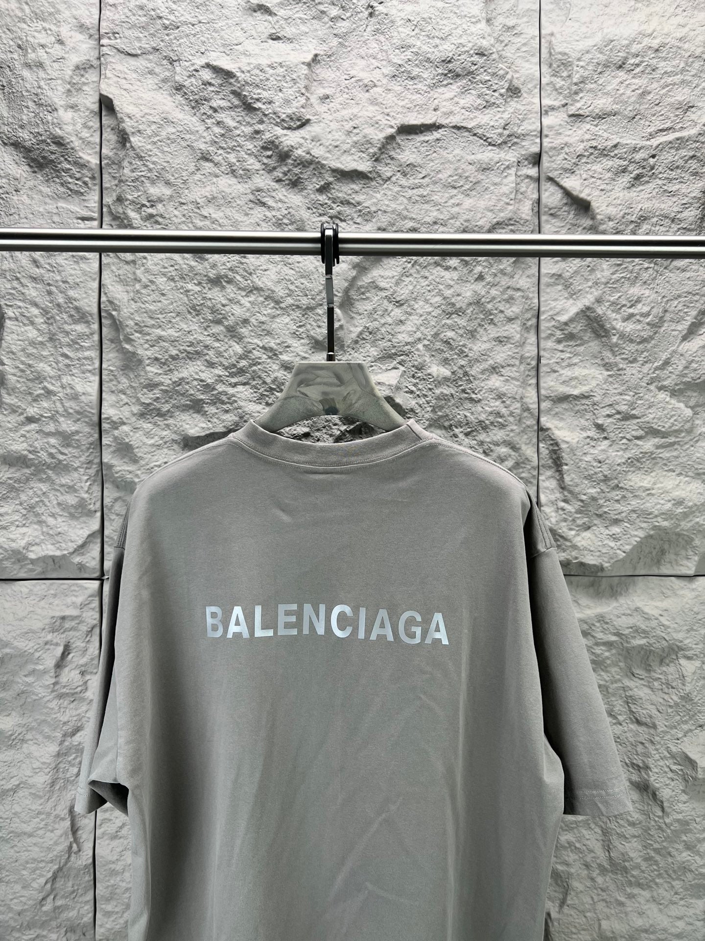 Light gray crewneck T-shirt front view on hanger, BALENCIAGA logo across chest
