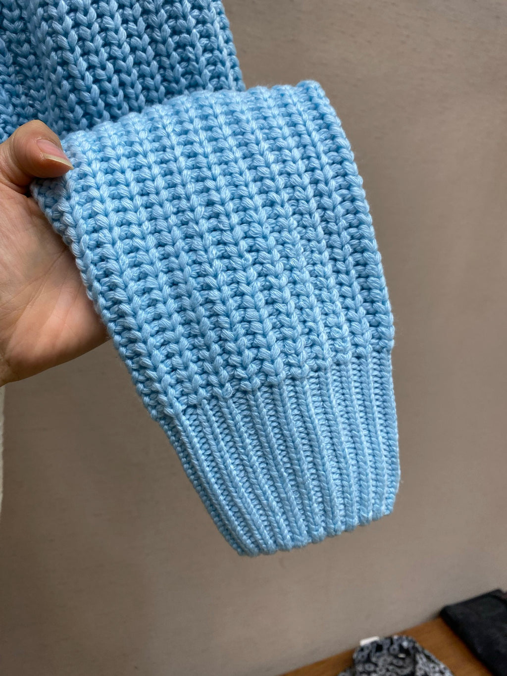 Light-blue knitted sweater cuff with ribbed texture